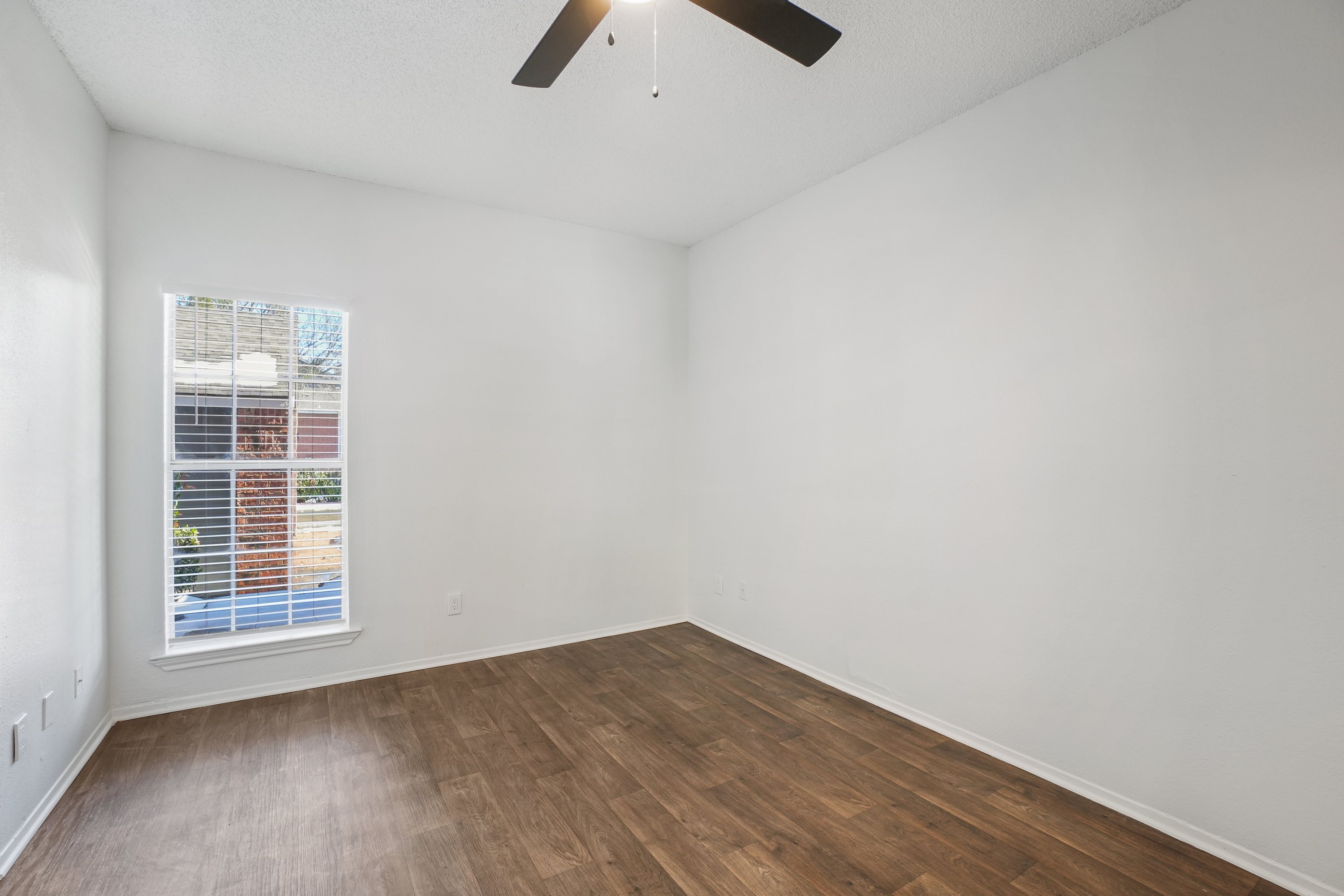 Empty room with a window and a ceiling fan.